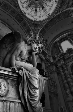 an angel statue sitting on top of a pedestal in front of a domed ceiling with ornate carvings