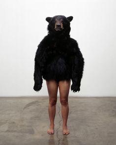 a person standing in front of a white wall with a large black bear on it's back