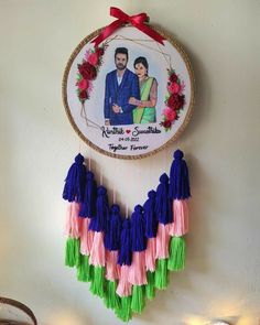 a couple's photo hanging on the wall with tassels in front of it