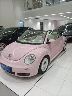 a pink car is parked in a showroom