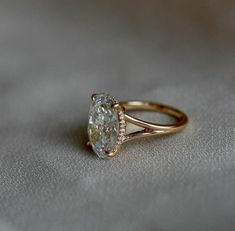 a close up of a ring on a white cloth with a diamond in the center