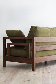 a green couch sitting on top of a hard wood floor next to a white wall