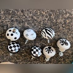 six knobs with black and white designs on them sitting on a granite counter top