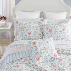 a white bed with pink and blue flowers on it