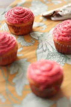 four pink cupcakes sitting on top of a table