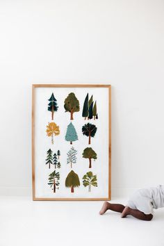 a young boy laying on the floor in front of a framed art print with trees