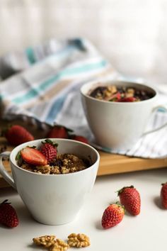 two bowls filled with cereal and strawberries on top of a white counter next to a cutting board