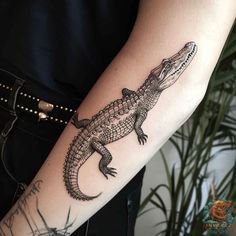 a woman's arm with a tattoo on it that has an alligator on it