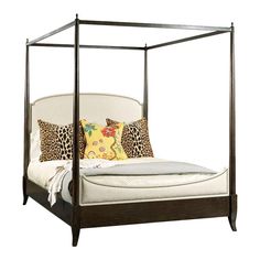 a four poster bed with leopard pillows on it's headboard and foot board