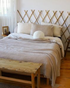 a bed with two pillows and a blanket on it, next to a wooden bench