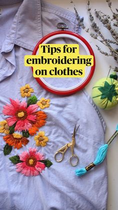 an embroidered shirt with flowers and scissors on it, next to some other crafting supplies