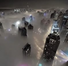 an aerial view of a city with skyscrapers and fog in the air at night