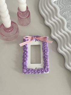 a purple and white photo frame sitting on top of a table next to two candles