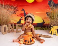 a baby is sitting on the floor in front of a lion themed backdrop and cake