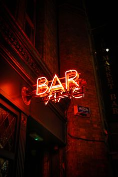 a neon sign that reads bar on the side of a building