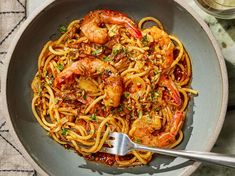 a bowl filled with pasta and shrimp on top of a table next to a fork