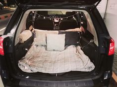 the back end of a car with pillows and blankets in it's trunk area