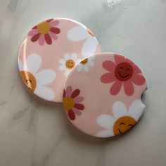 two pink and yellow flowered plates sitting on top of a white countertop next to each other