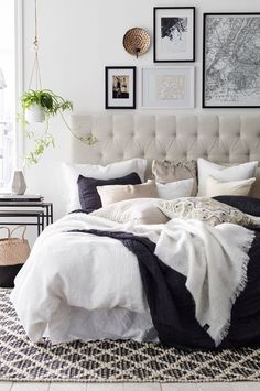 a bedroom with white walls and black and white bedding, pictures on the wall