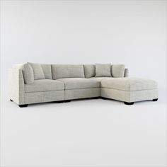 a large sectional couch with pillows on the back and arms, sitting in front of a white wall