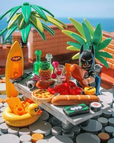 a table topped with lots of toys and food next to a palm tree on top of a roof