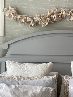 a bed with two pillows and some paper flowers on the headboard, along with other decorative items