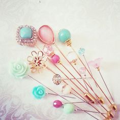 a bunch of pins sitting next to each other on a white tablecloth with pink, blue and green flowers