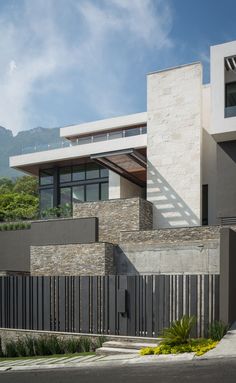 a modern house with stone walls and stairs leading up to the front door, on a sunny day