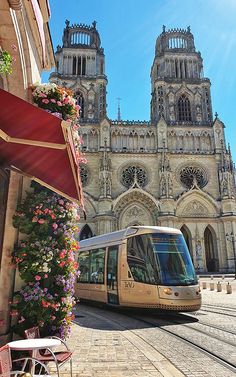 a bus parked in front of a building with flowers growing on it's side