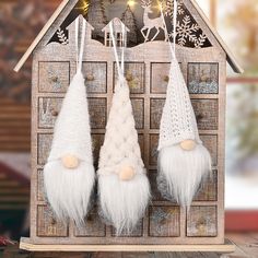 three white christmas decorations hanging from a wooden house