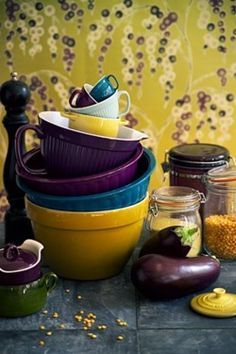 a stack of colorful dishes sitting on top of a table next to jars and containers