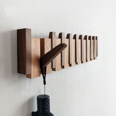 a wall mounted wooden object on the side of a wall next to a black vase