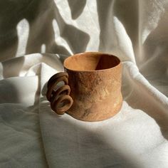 a clay cup sitting on top of a white cloth