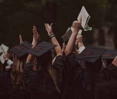 graduates raising their hands in the air with books and papers on their heads at graduation