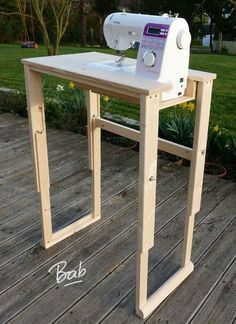 a sewing machine sitting on top of a wooden table next to a flower pot and grass