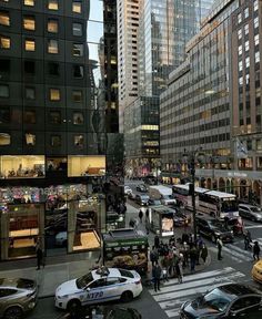 a busy city street filled with lots of traffic and tall buildings in the evening hours