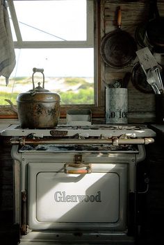 an old fashioned stove with pots and pans on the burners in front of a window