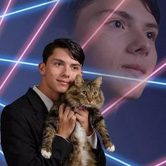 a young man holding a cat in front of a poster with a woman's face