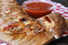 some food is laying on a cutting board with a bowl of sauce in the background