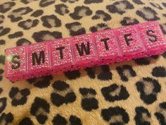 the word smtwtfs spelled out with pink beads on a leopard print background