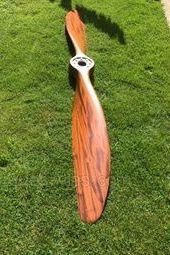 an orange propeller sitting on top of a green grass covered field next to a sidewalk