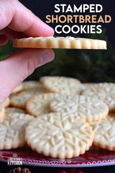 a hand is holding a shortbread cookie on a plate