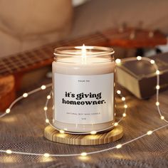 a candle that says it's giving homeowner sitting next to a guitar