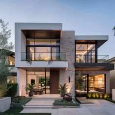 a modern house with large windows and plants in the front yard