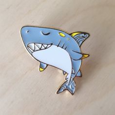 a blue and white shark pin sitting on top of a wooden table with it's mouth open