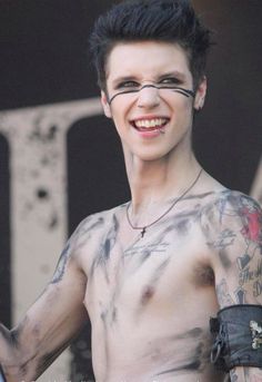 a man with tattoos on his chest smiling