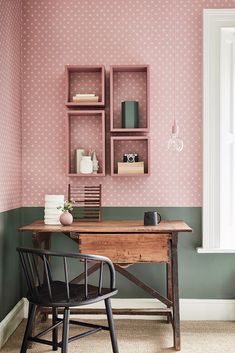 a desk and chair in a room with pink wallpaper