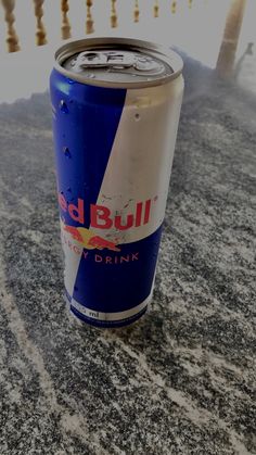 a can of red bull drink sitting on the ground