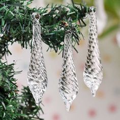 three glass ornaments hanging from a tree branch