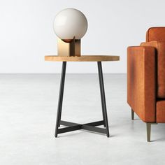 an orange chair and table with a white ball on it in front of a couch